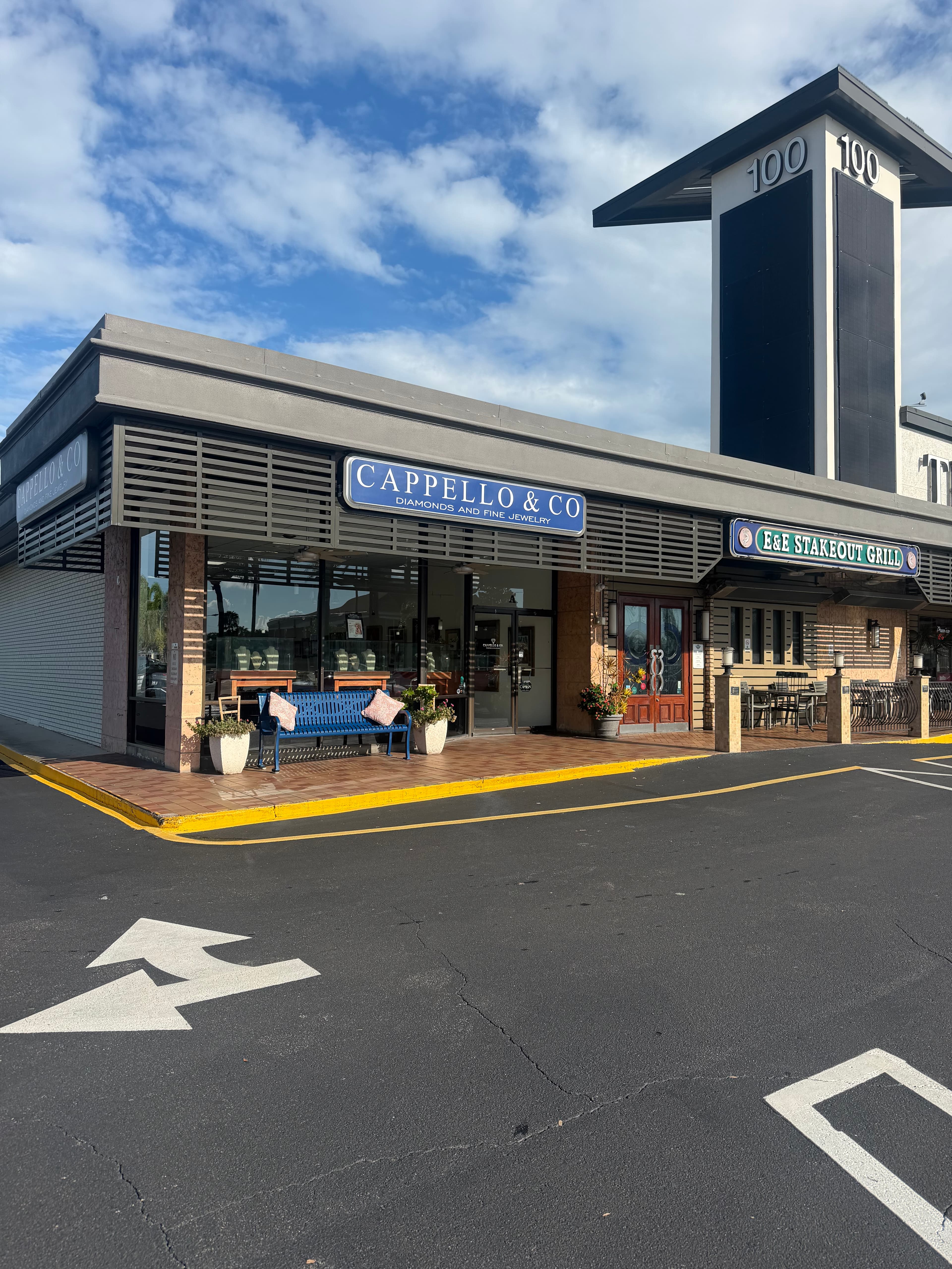 Cappello & Co corner storefront in Belleair Bluffs with blue signage and a blue bench outside